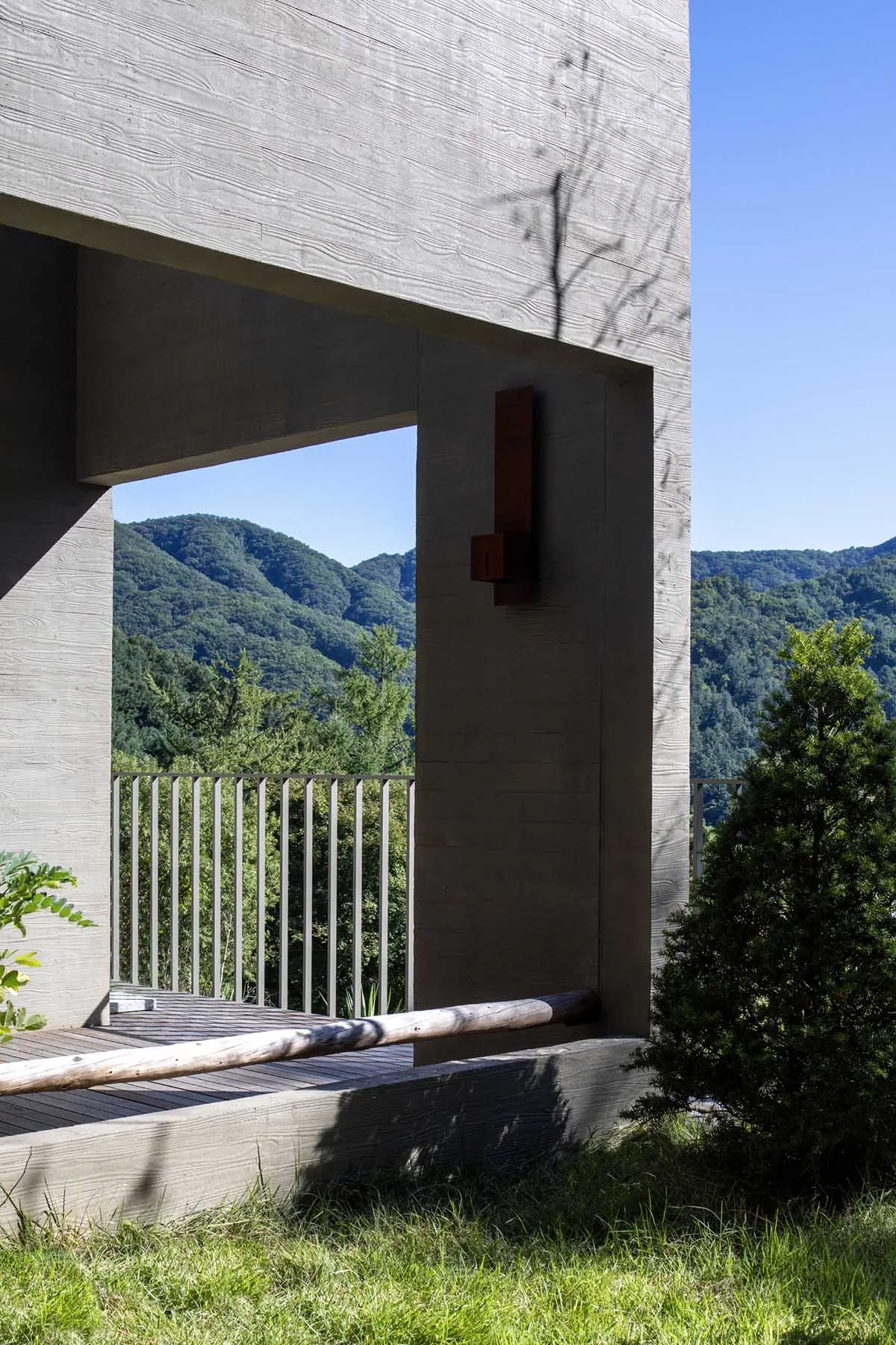 Modern residential building with concrete exterior and terrace overlooking mountains.