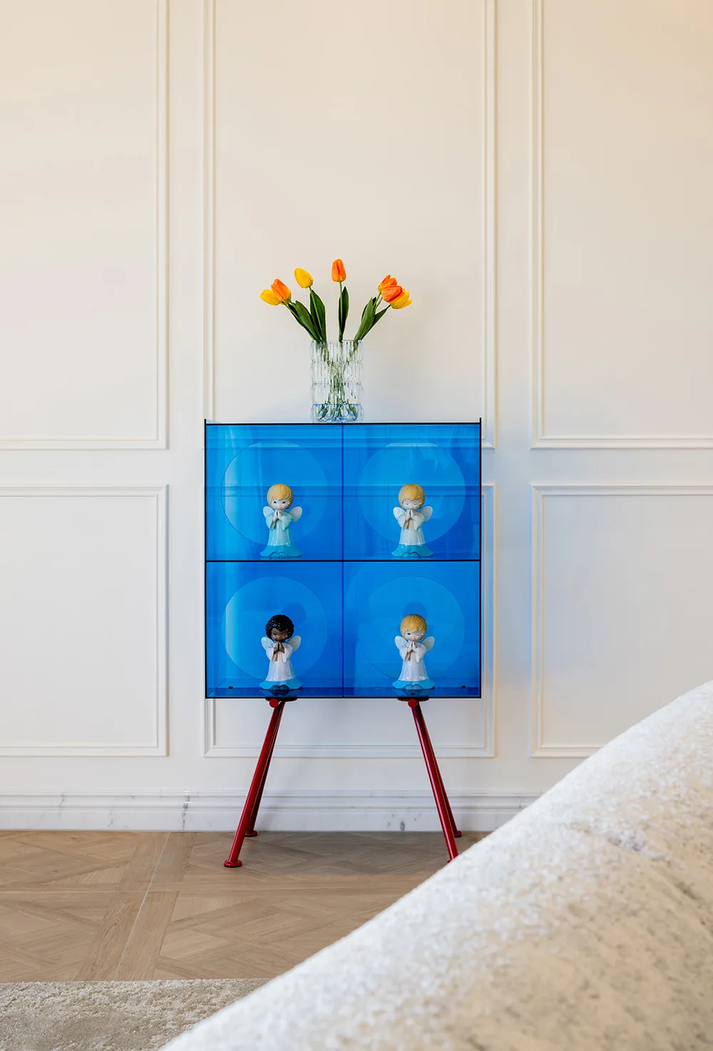 A modern blue shelf decor featuring tulips and figurines in a living room setting.