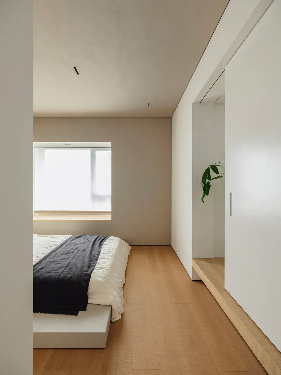 A minimalist bedroom featuring a wooden floor, metallic headboard, and fabric bedding.