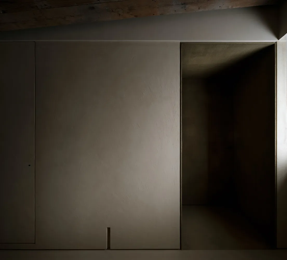A minimalist concrete interior with a door leading to another space.