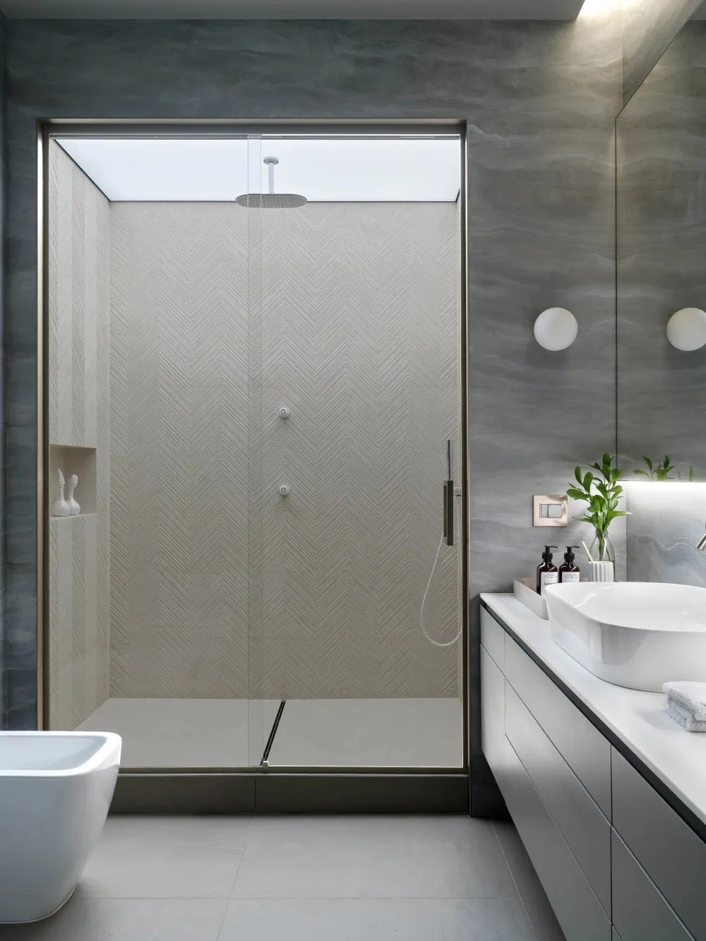 Modern bathroom with grey tile shower room featuring minimalist design and glass shower enclosure.