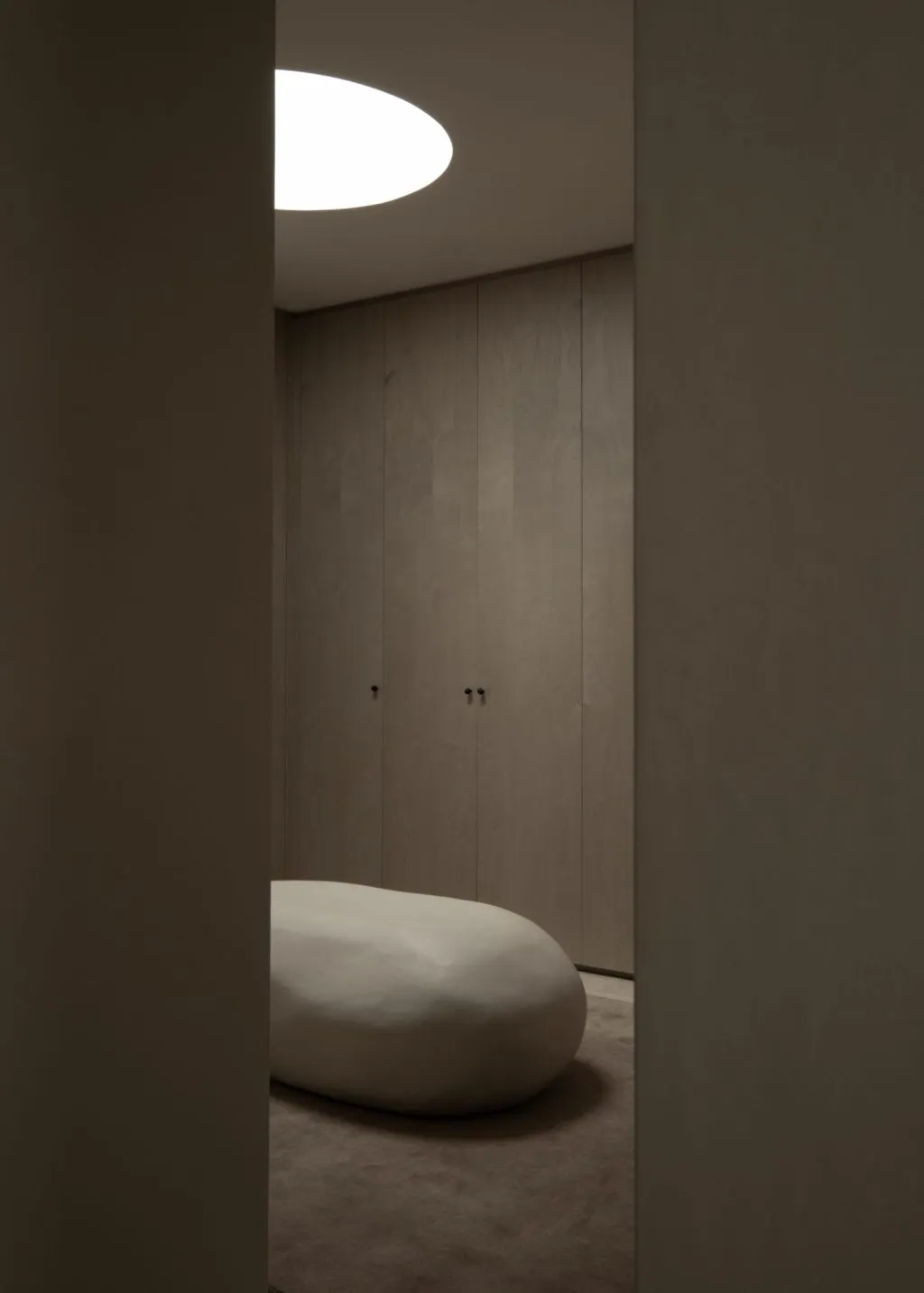 A minimalist interior space featuring wooden cabinets and a large oval seat