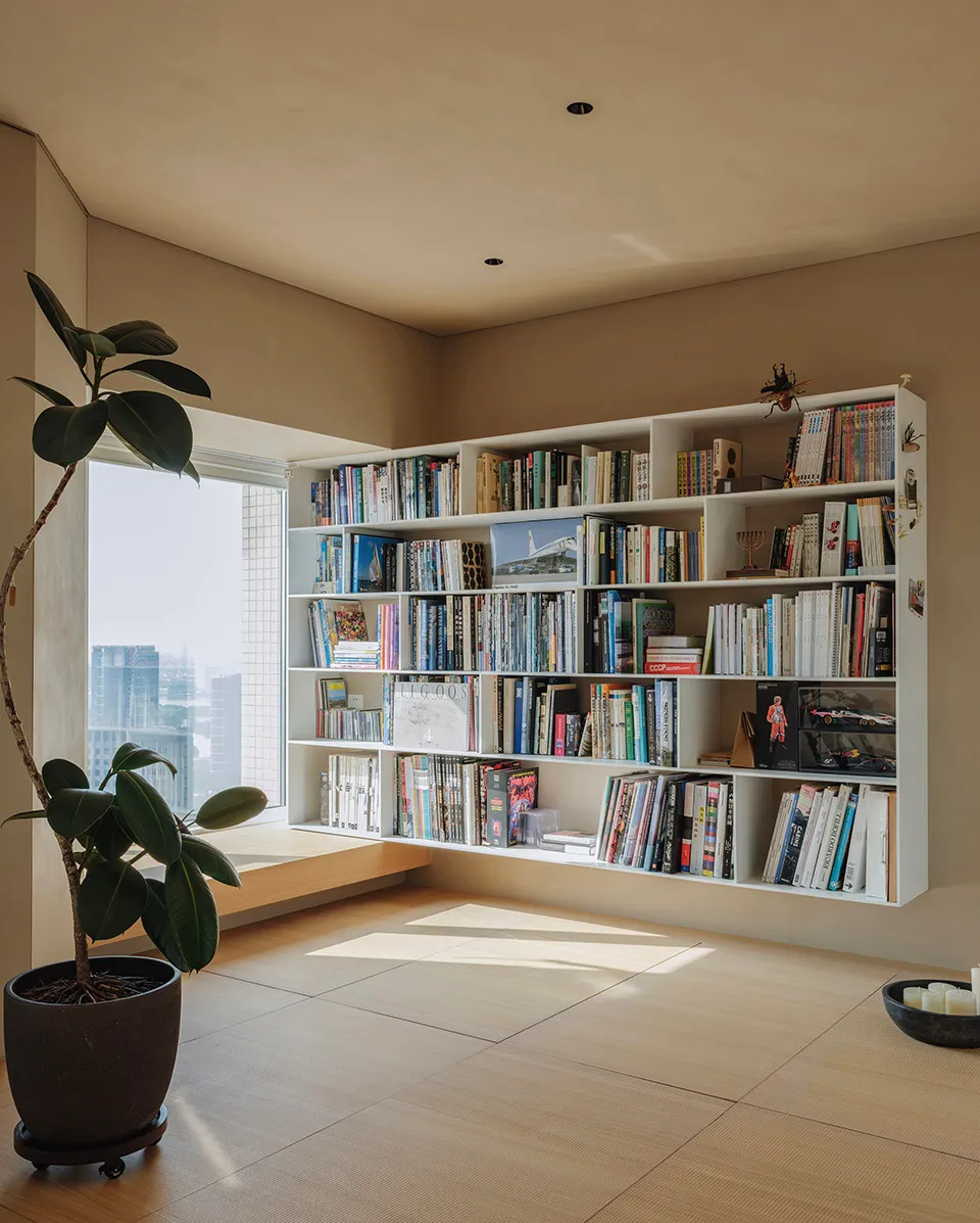 A modern floating bookshelf filled with books and decorative items, positioned by a large window with views of a city skyline