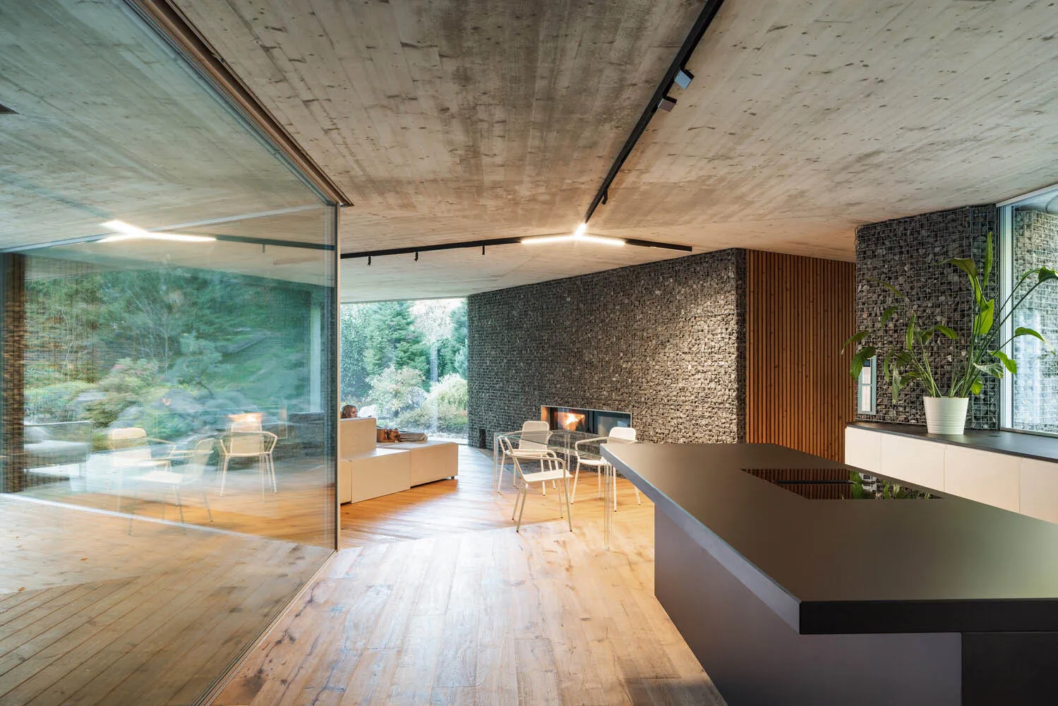 Modern living room with concrete walls, wooden floors, and stone accents