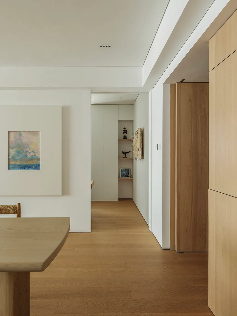Minimalist dining room with a wooden floor and table, featuring a simple and clean design aesthetic.