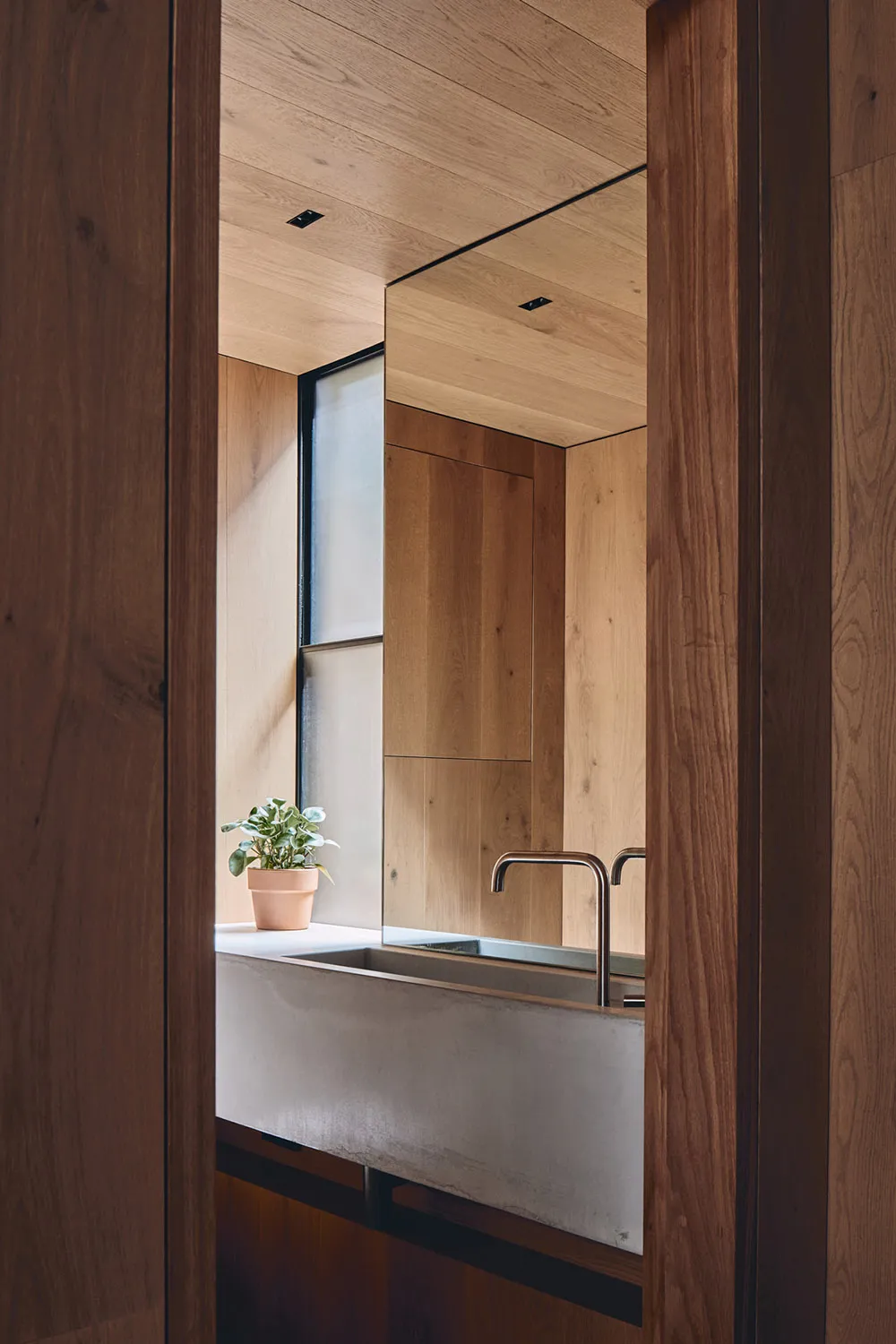 A modern bathroom with a concrete sink and wooden walls and ceiling.