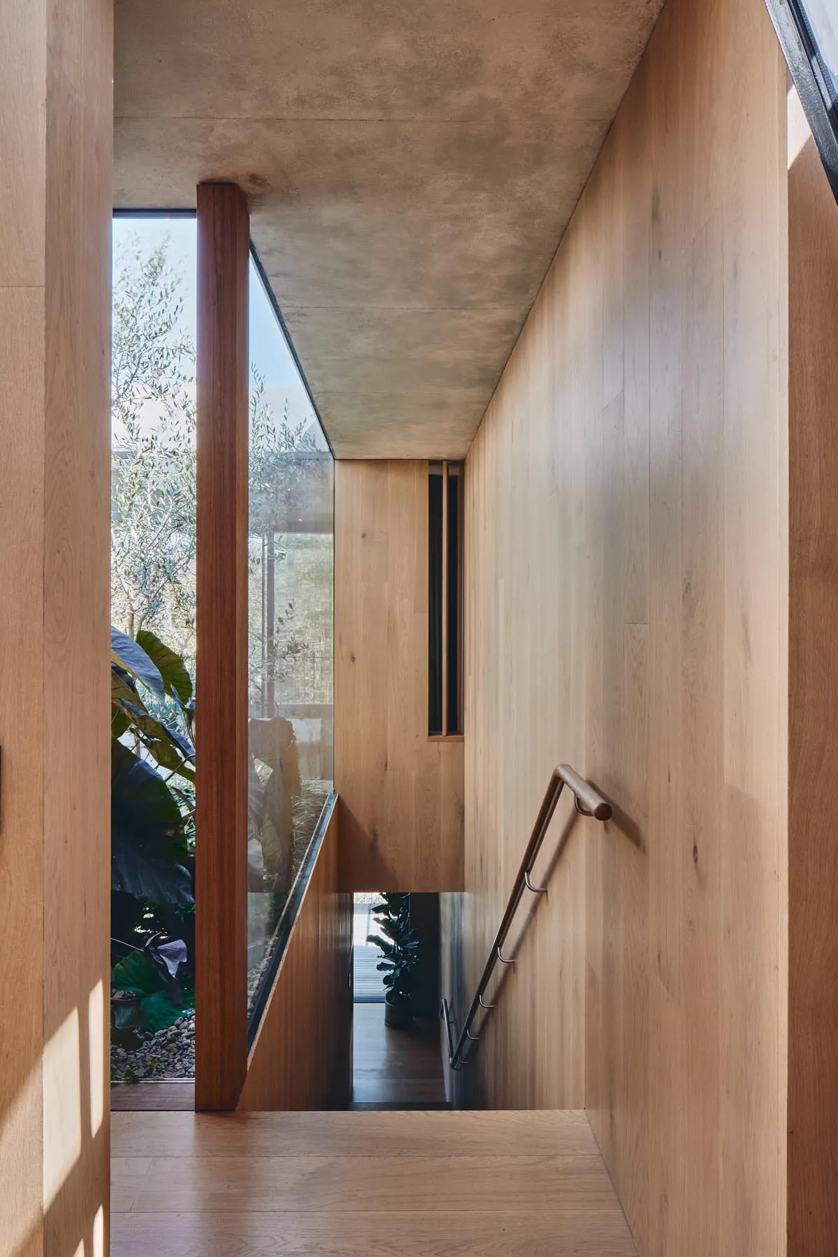 A modern interior with a wooden staircase and glass wall, featuring a sleek, contemporary design.