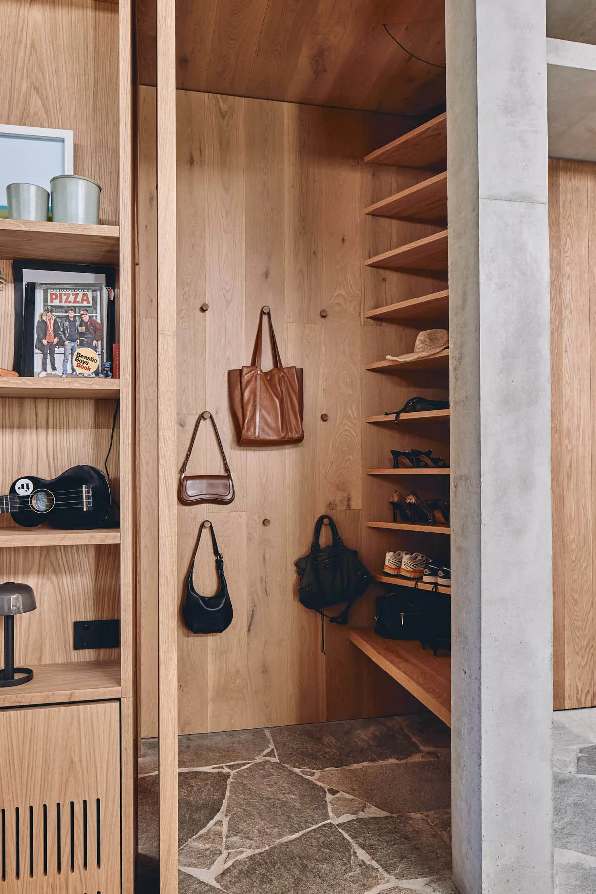 A modern wooden storage space with shelves and wall hooks.
