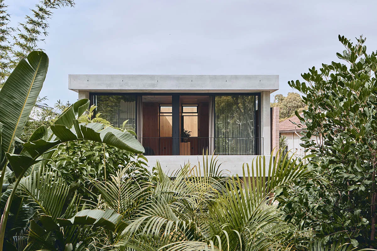 A modern residential building with a concrete exterior and large glass windows.