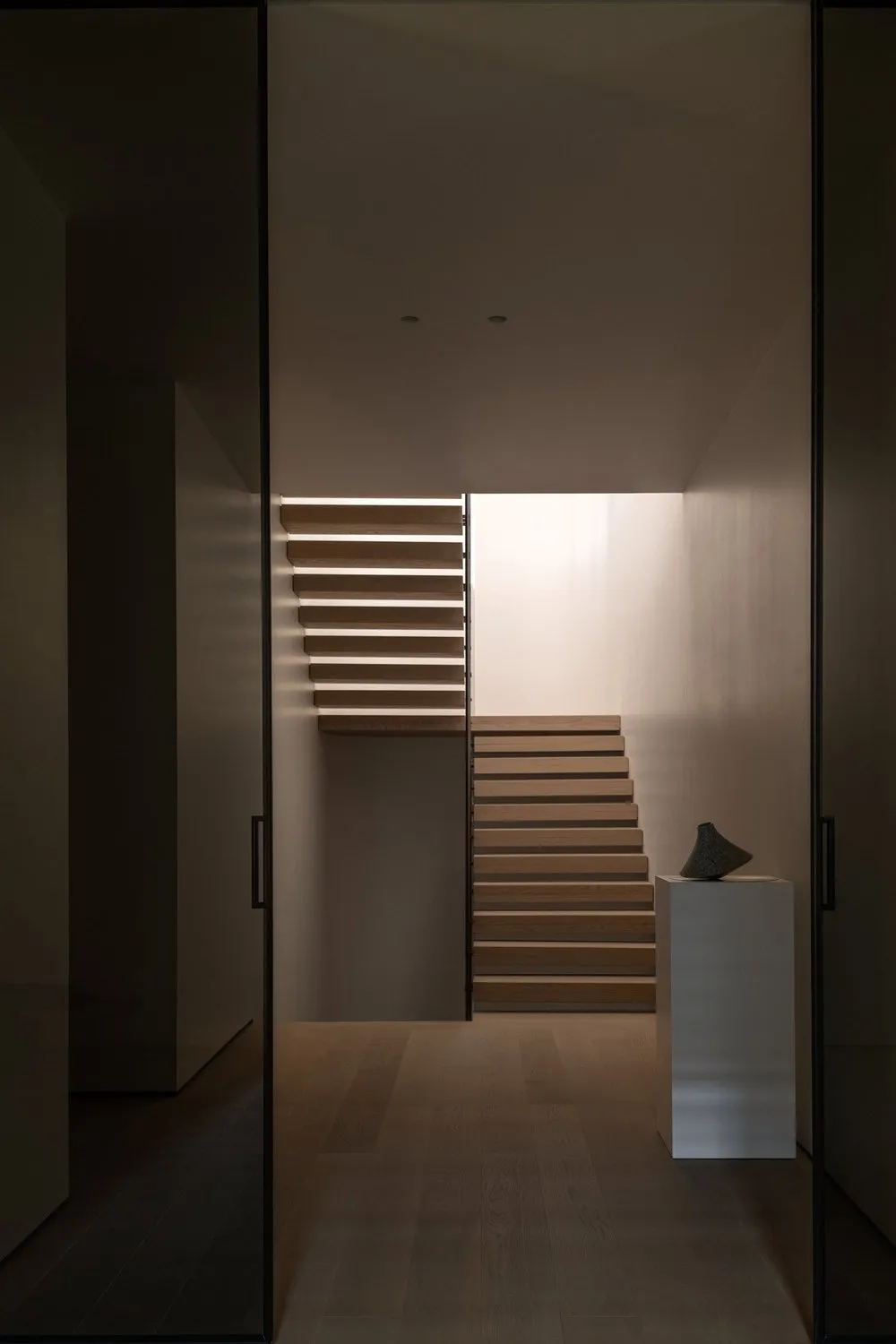 A modern staircase interior with wooden steps and illuminated railings.