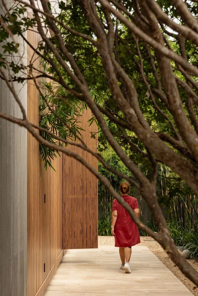 A modern building with wooden exterior, viewed through tree branches.