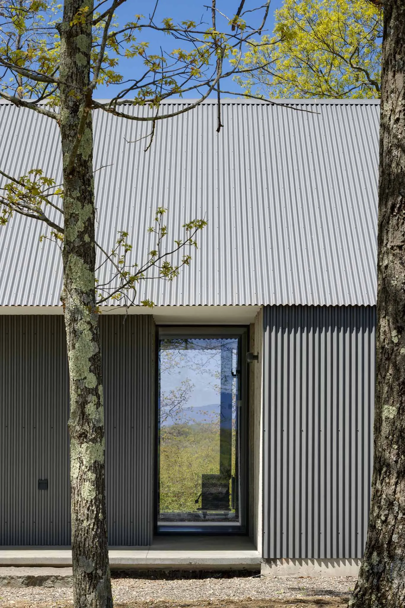 Modern house exterior with corrugated metal siding and large window.
