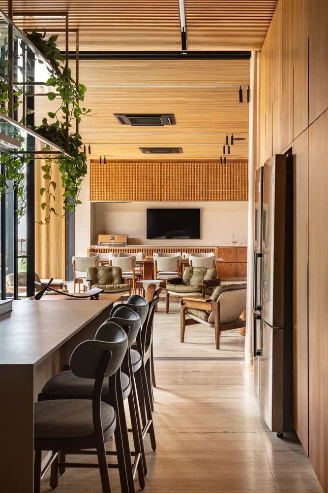 A modern bistro interior with a wooden counter, chairs, and a television in the background.