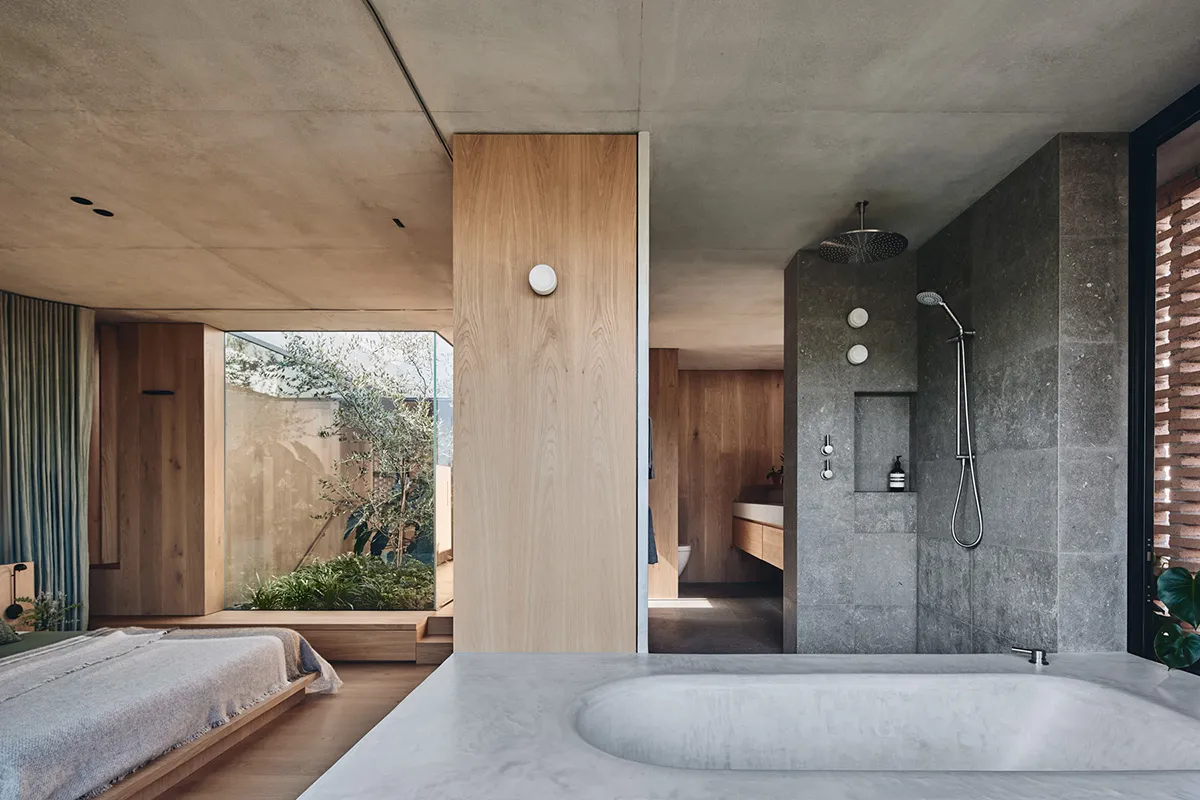 A modern bathroom interior featuring a large concrete bathtub and wooden accents.