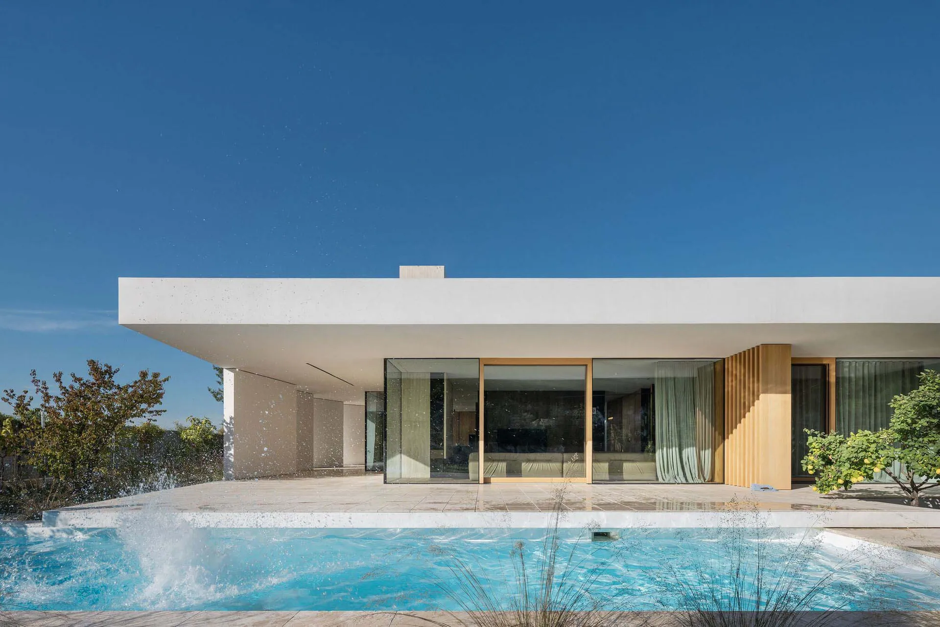 A modern house featuring concrete walls and a pool outdoors.