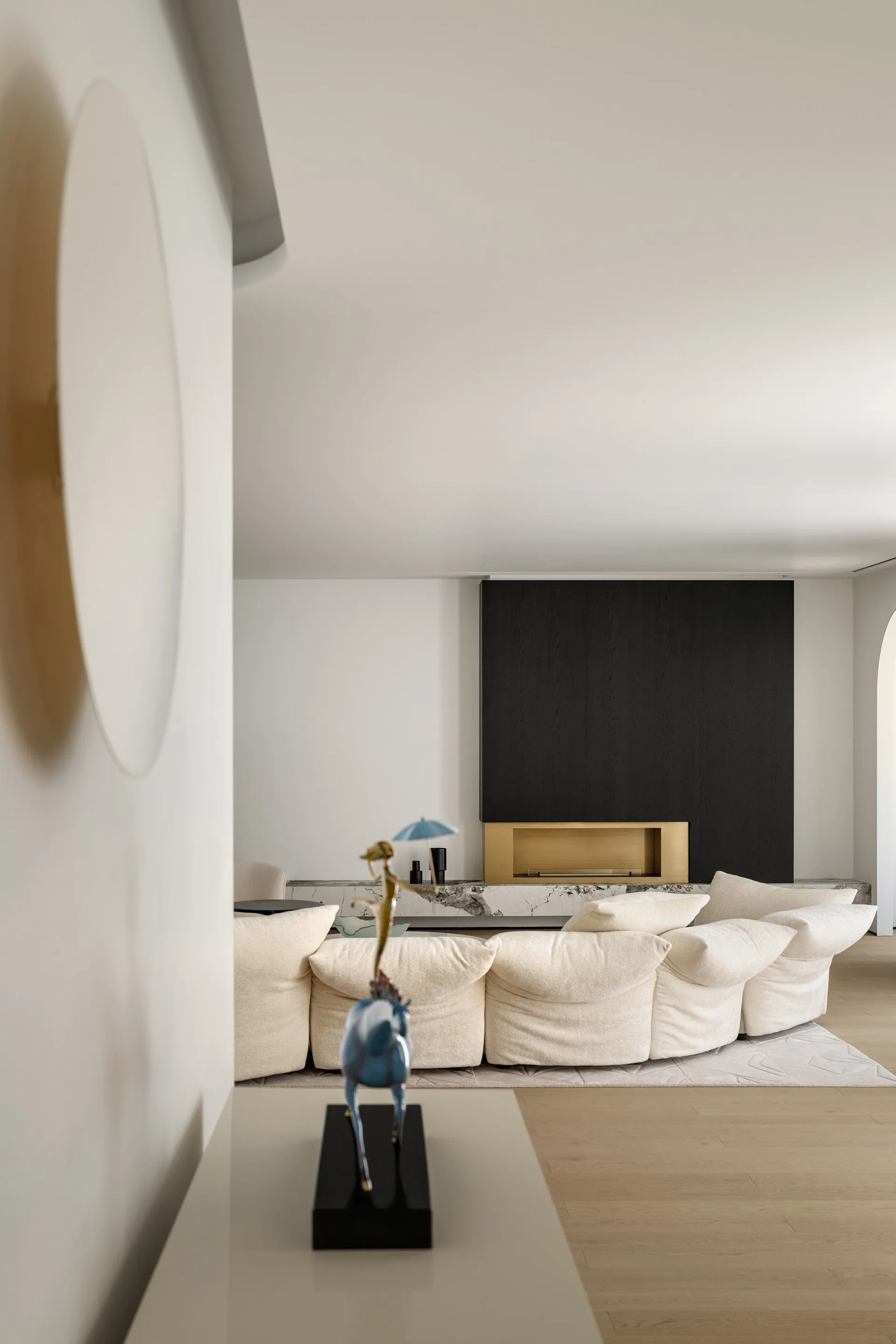 Modern living room featuring a white marble fireplace and a large beige sofa.