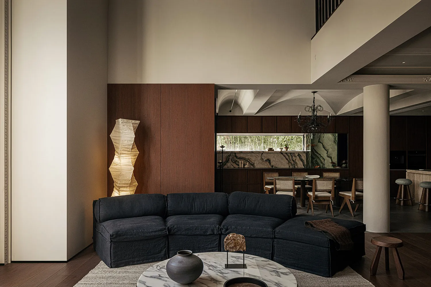 Modern living room featuring dark blue fabric sofa, marble coffee table, and wooden flooring.