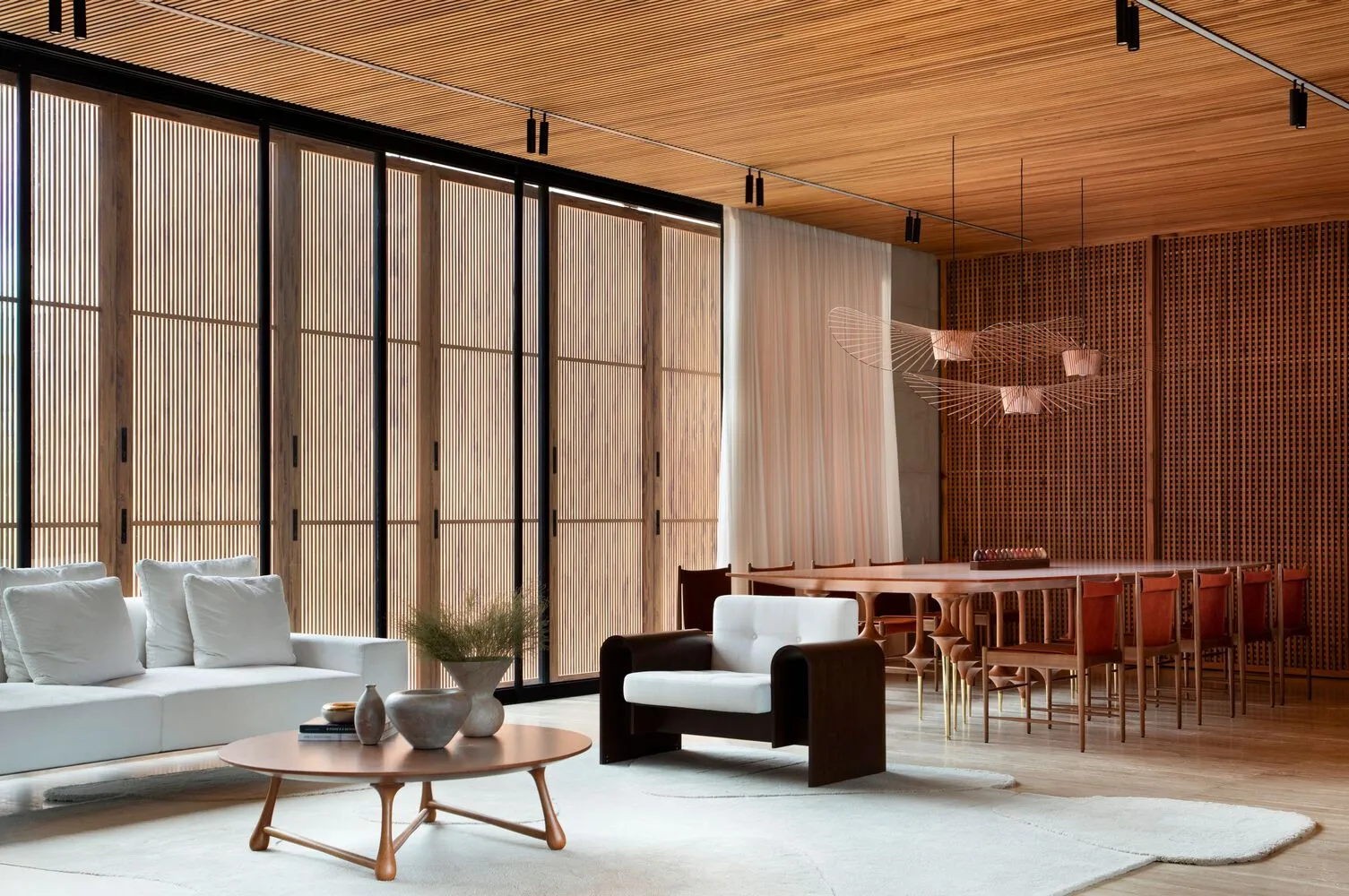 Modern living room with white furniture, wooden ceiling, and large windows