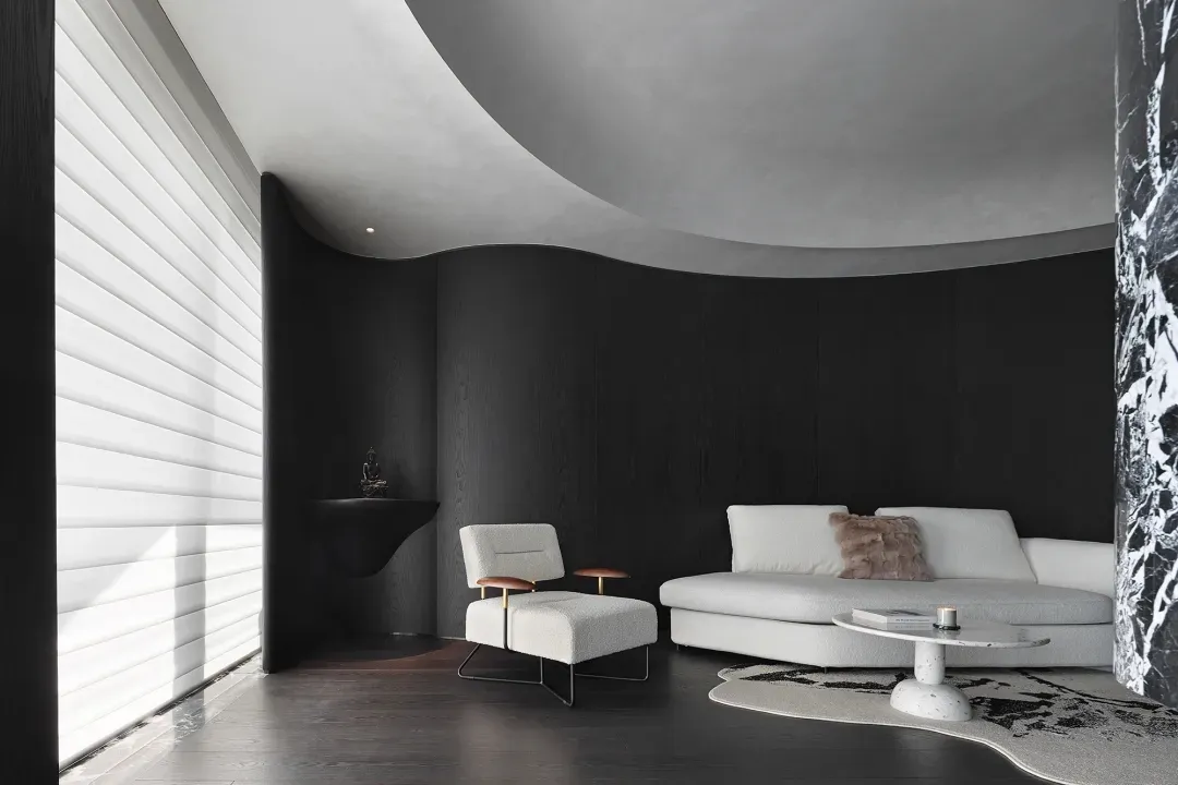 A minimalist living room featuring a white sofa, a white armchair, and a concrete wall