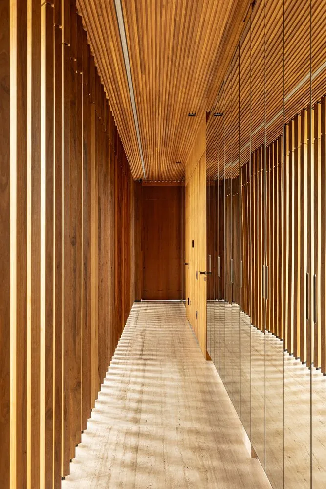 Modern corridor with wooden walls and ceiling, featuring a long hallway with wooden panels.