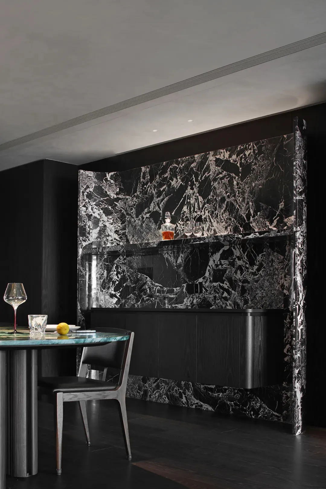 A modern industrial bar counter made of marble with black and white veins, featuring a sleek design with a single chair and a