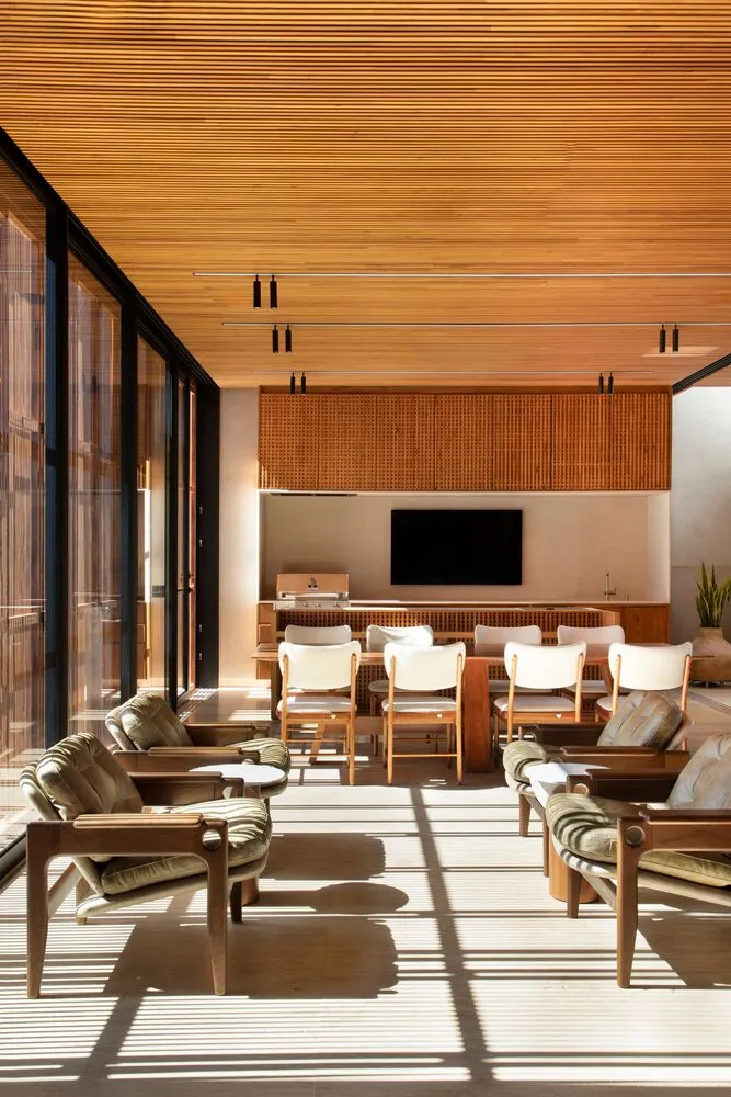Modern living room with wooden walls and floors, white furniture, and a flat-screen TV.