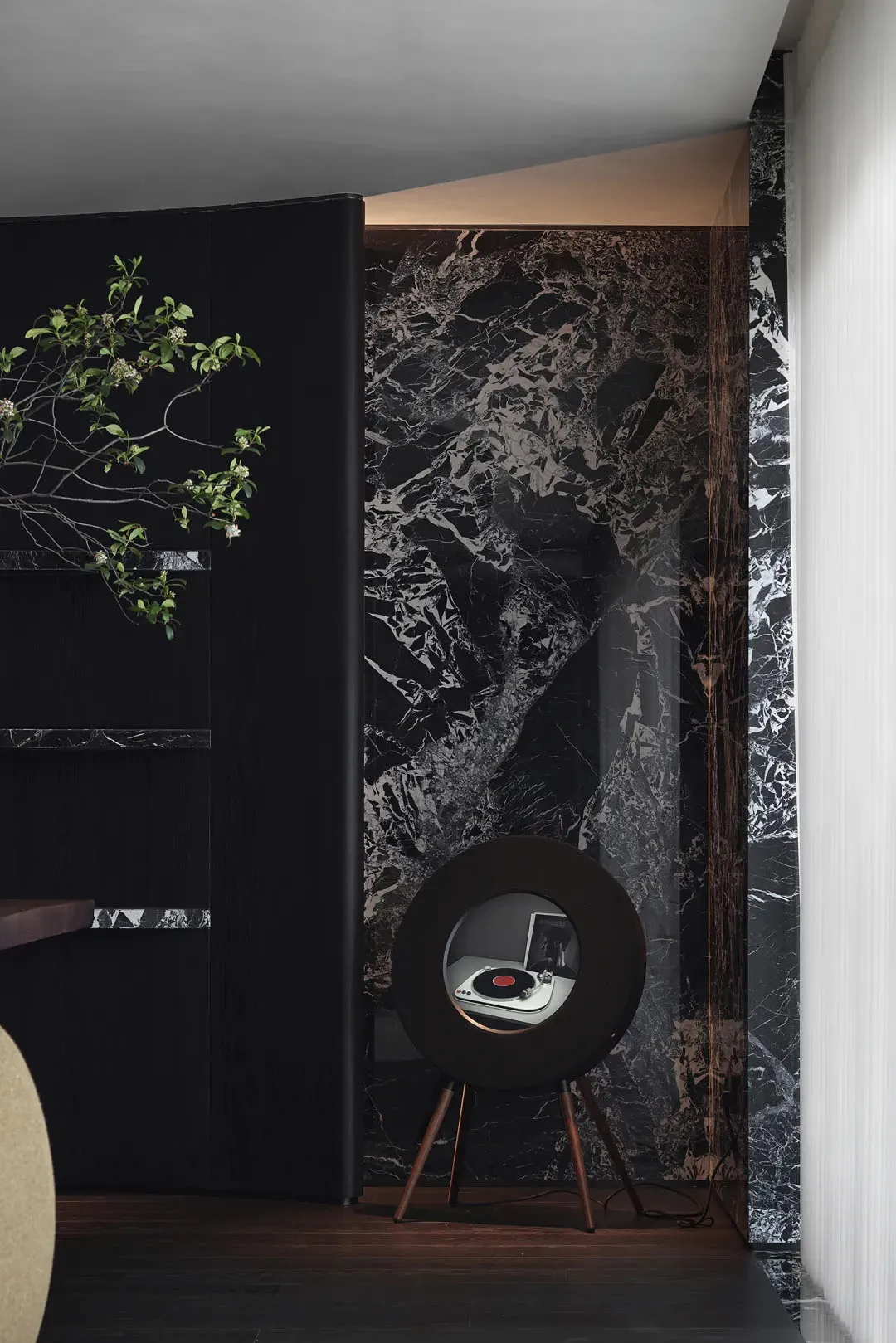 A modern living room featuring marble walls and a sleek, round speaker.