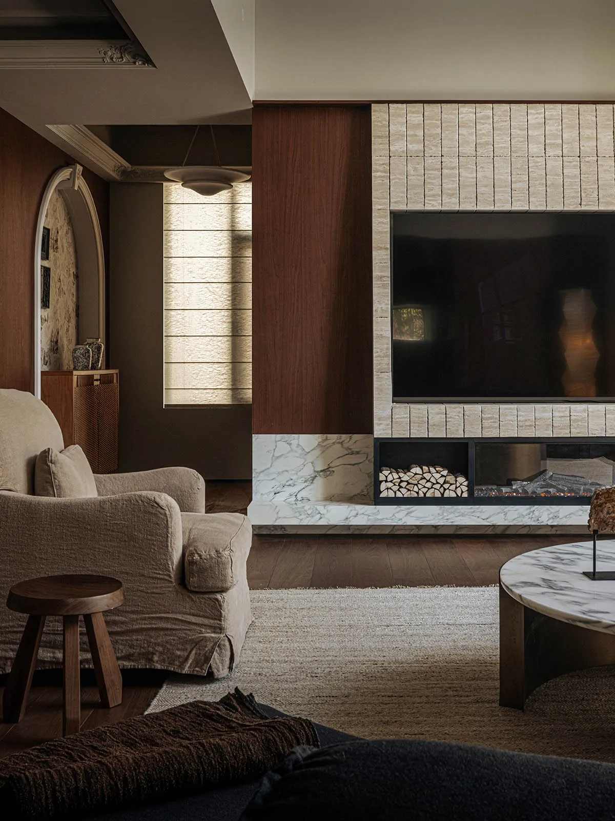 A modern living room featuring a marble fireplace with wood accents and a cozy seating arrangement.
