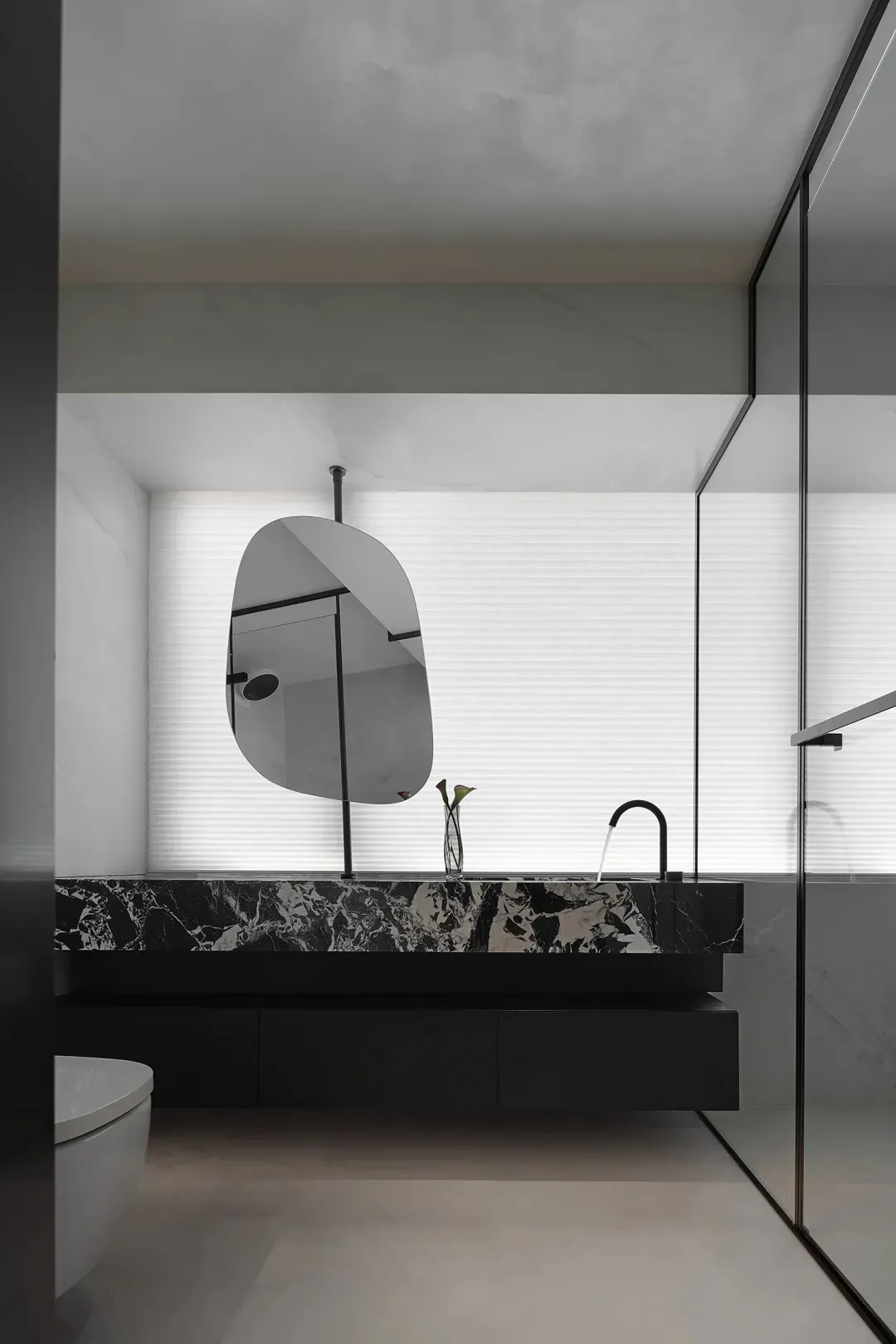 Modern minimalist bathroom with marble elements and a unique mirror hanging in front of the window.