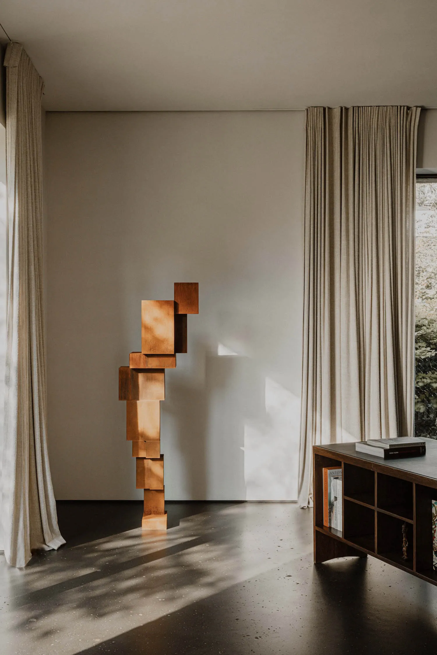 A modern interior living space featuring corten steel art sculpture and natural light.