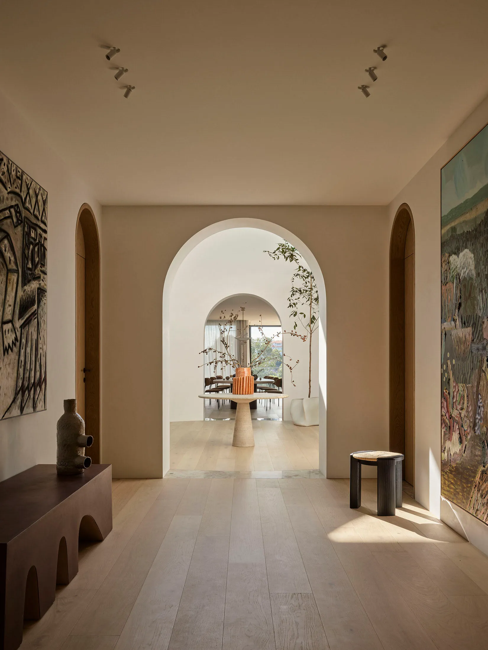 A modern interior with light timber flooring, white walls, and arched doorways.