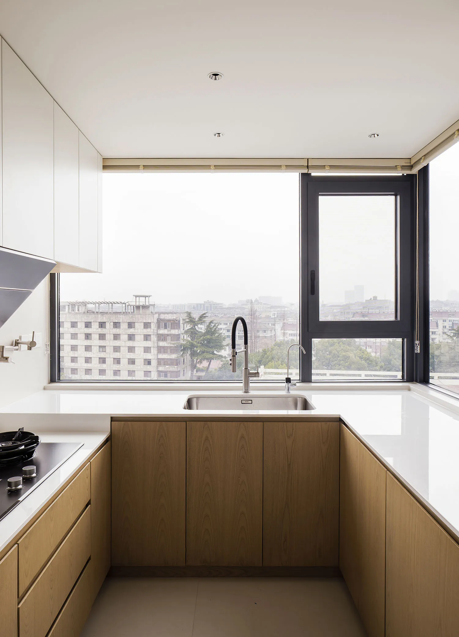 A modern, minimalist kitchen featuring wooden cabinets, glass windows, and stainless steel appliances.