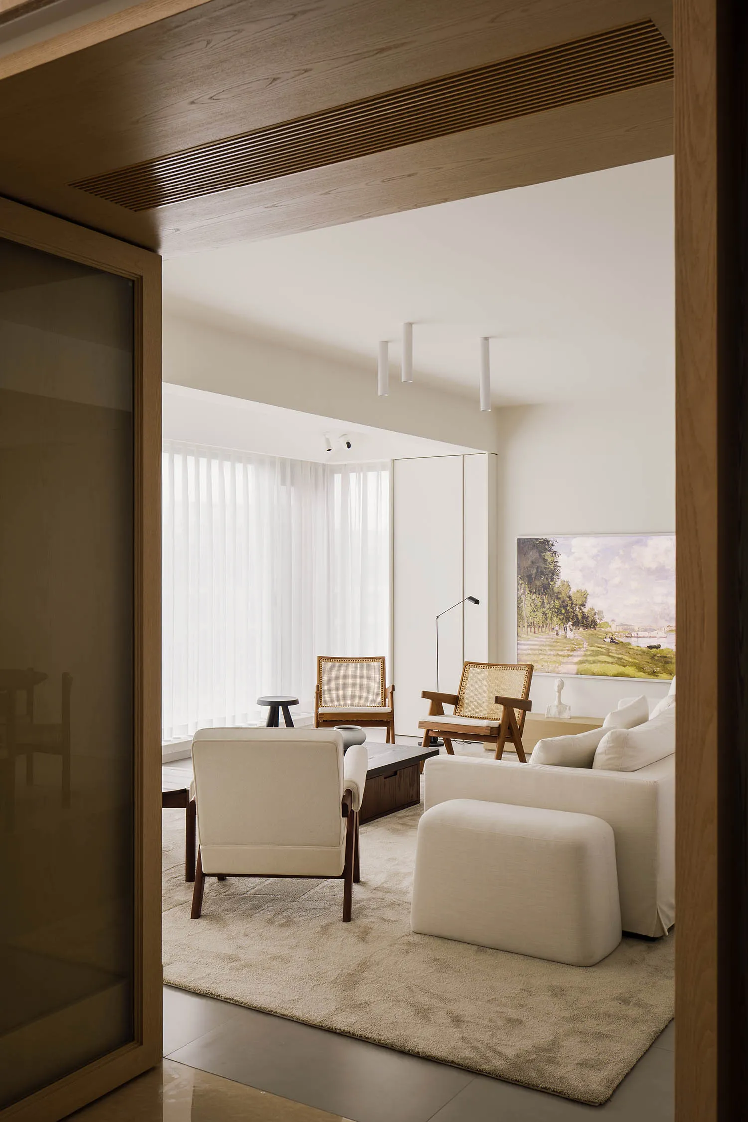 Spacious modern minimalist living room with white fabrics, wooden furniture, and glass elements.