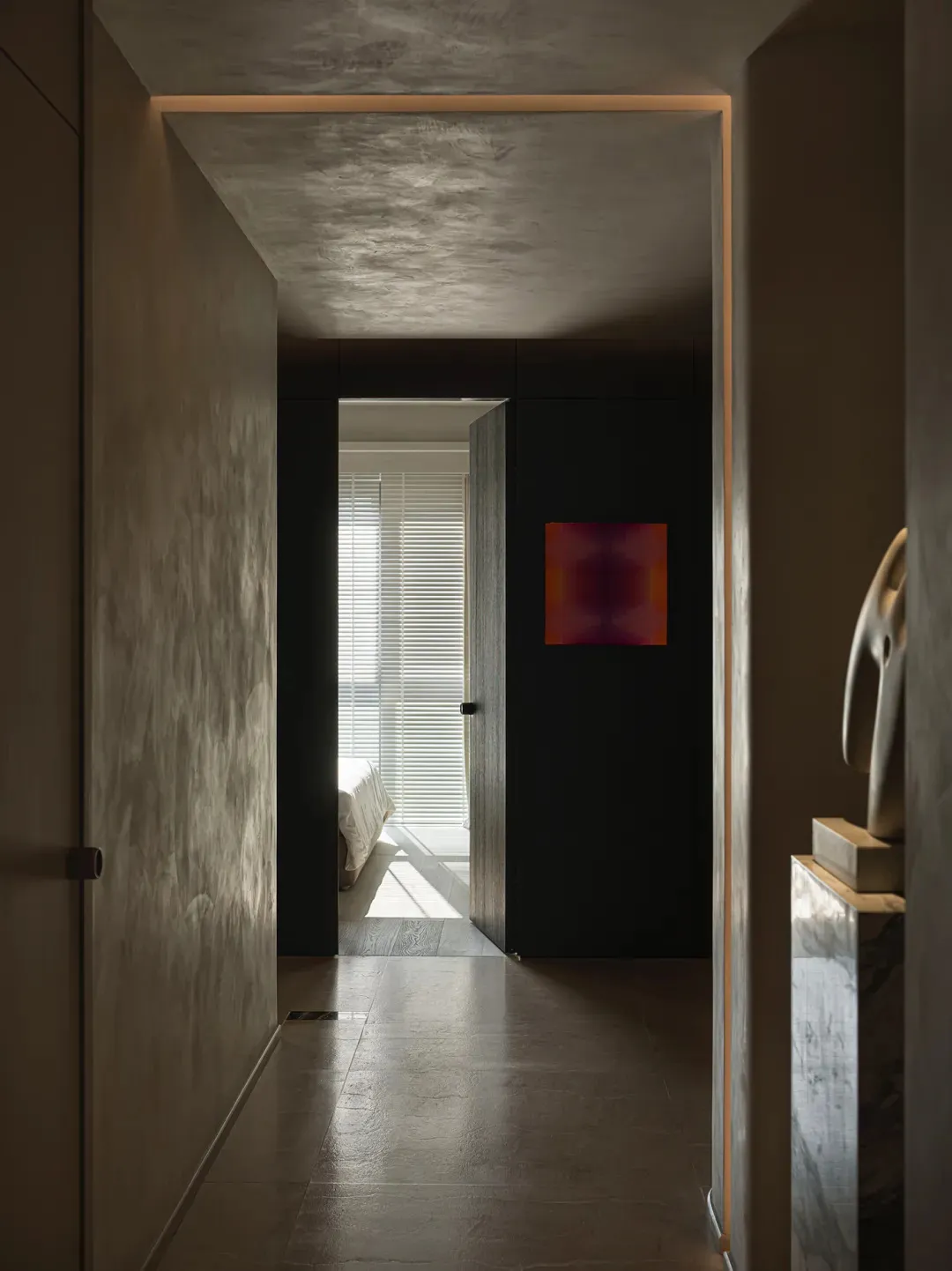 A glimpse into a minimalist interior design space featuring a concrete floor and a modern artwork on a black wall.