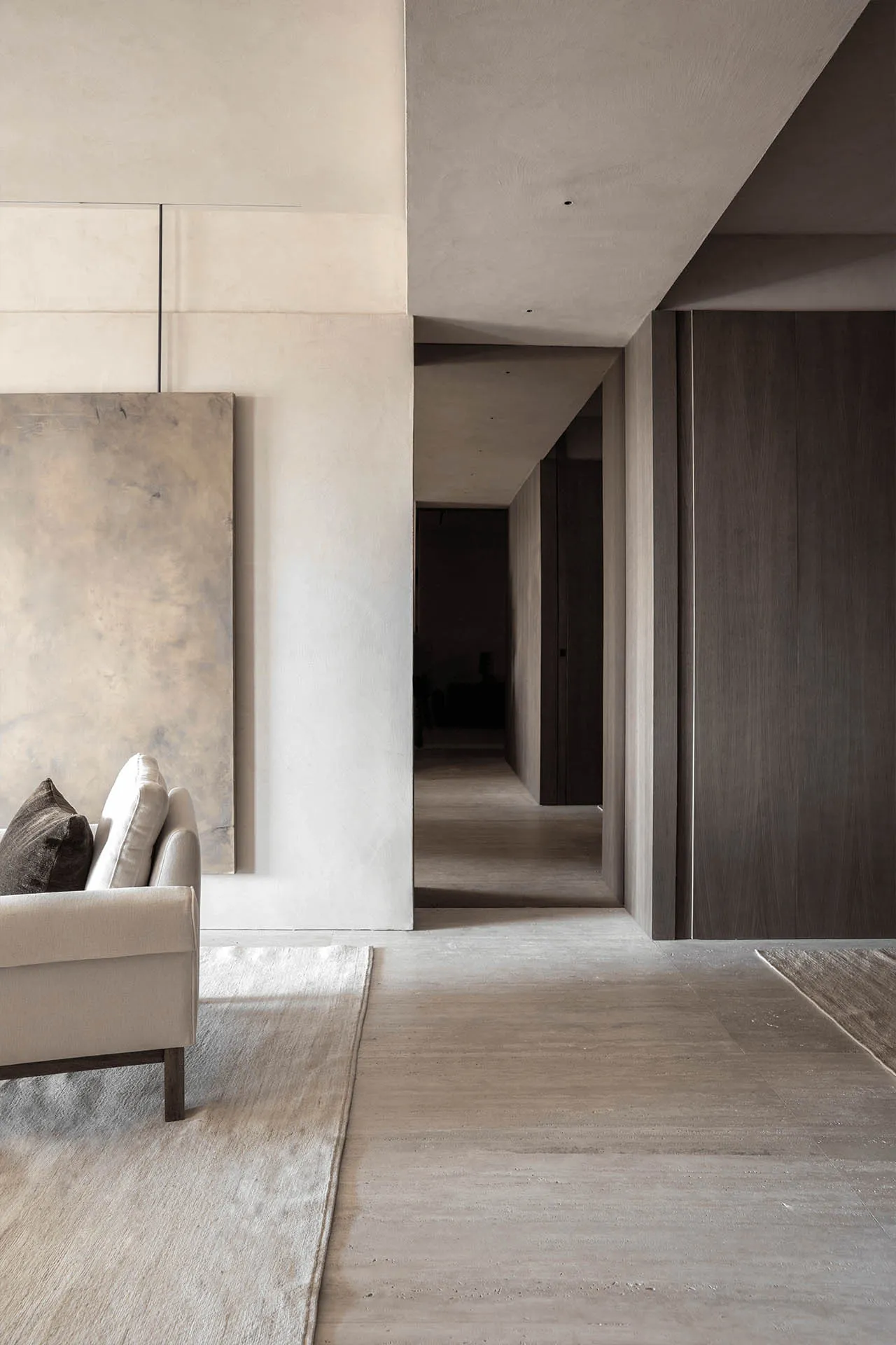 A minimalist living space featuring natural light, concrete flooring, and wood accents.