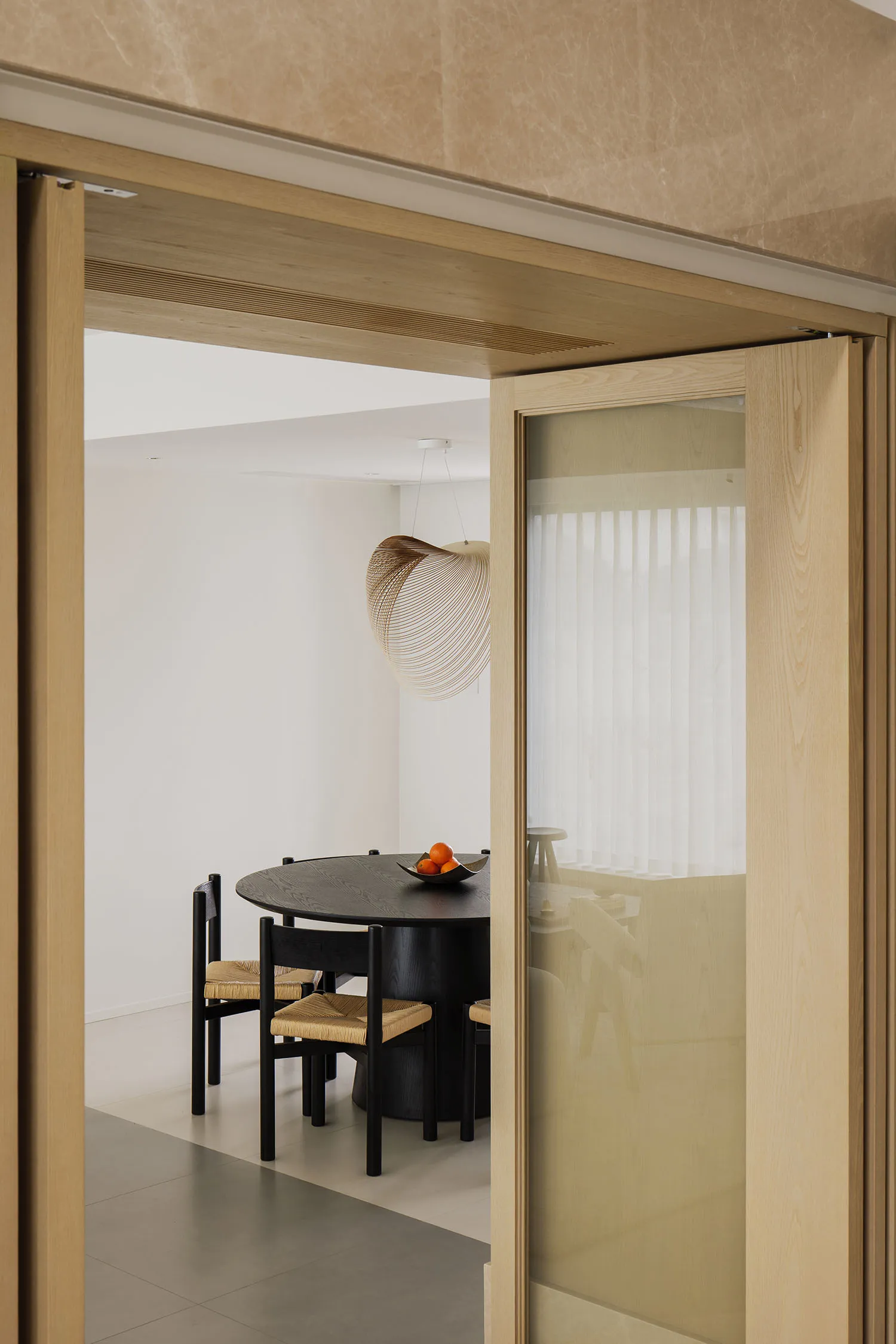 A modern dining room featuring wooden furniture and a round table with hanging lamps.