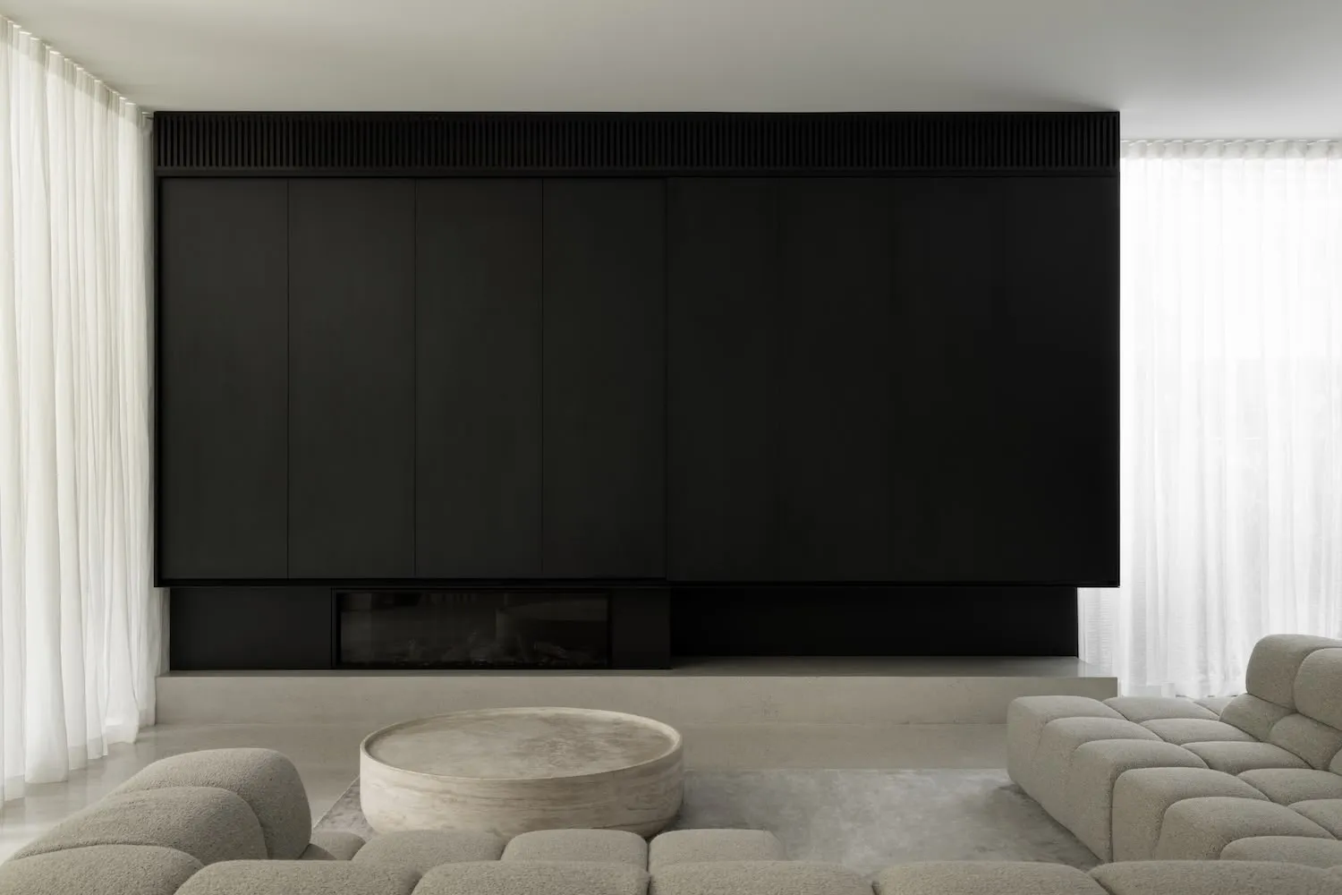 Modern minimalist living room with concrete walls and floors, featuring a large sofa and a stylish coffee table.