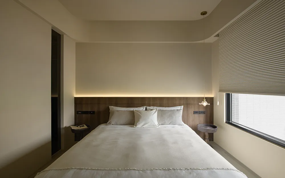 Modern minimalist bedroom with a wooden wall, white bedding, and a sleek, contemporary style.
