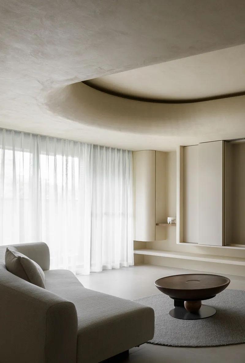 Modern minimalist living room with concrete walls, fabric sofa, and sheer curtains.