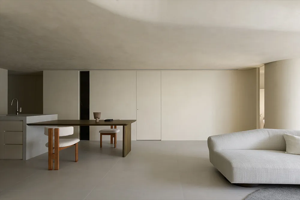 Minimalist modern interior design featuring sleek, concrete walls, wooden furniture, and fabric seating.