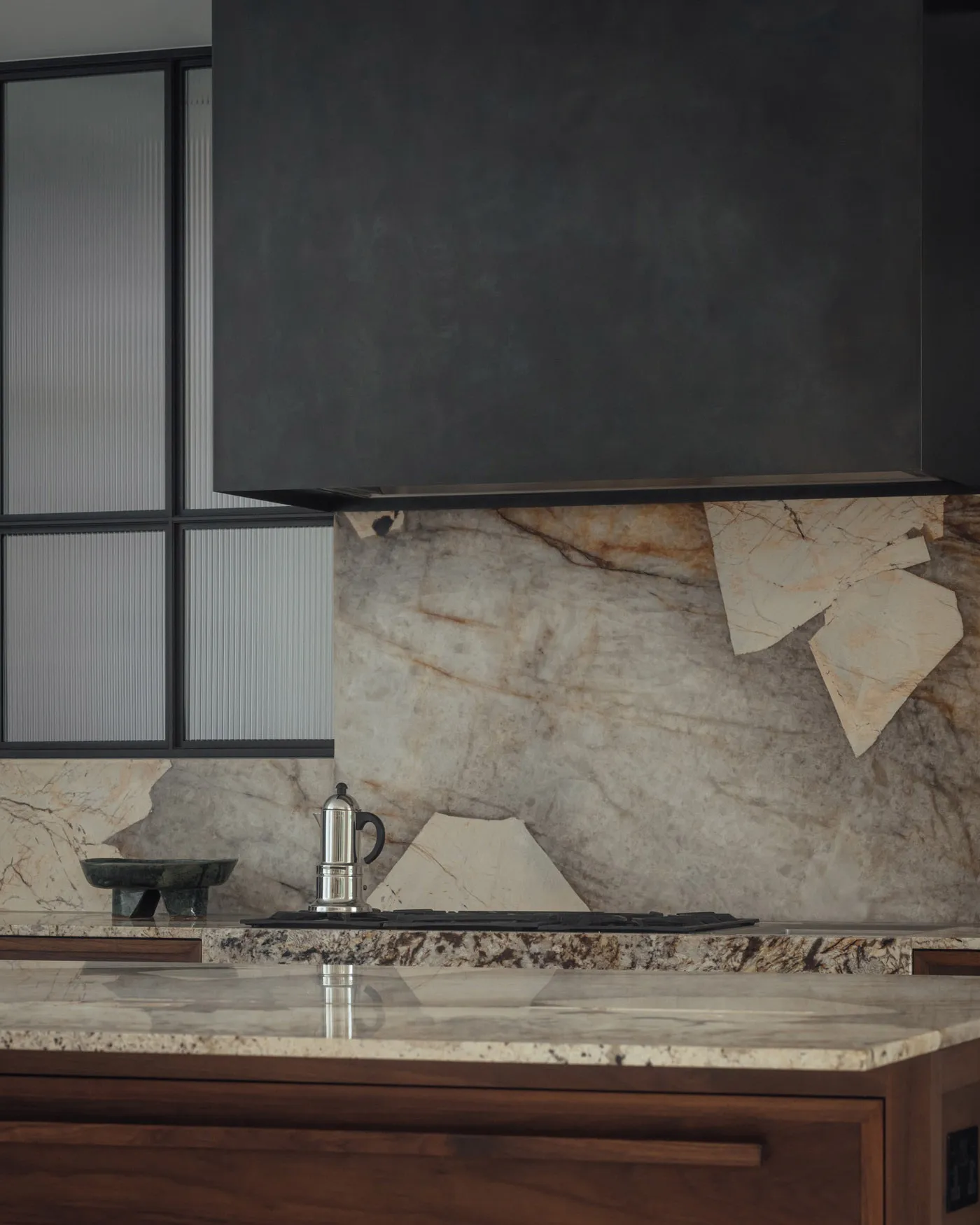 Modern kitchen featuring a sleek marble backsplash and countertop, with a stainless steel espresso maker on the countertop.
