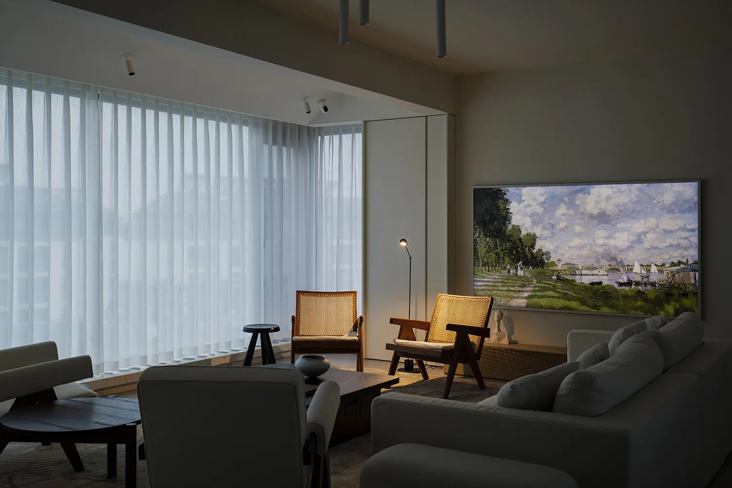 A well-lit, modern living room featuring fabric furniture and curtains, with a large painting on the wall.