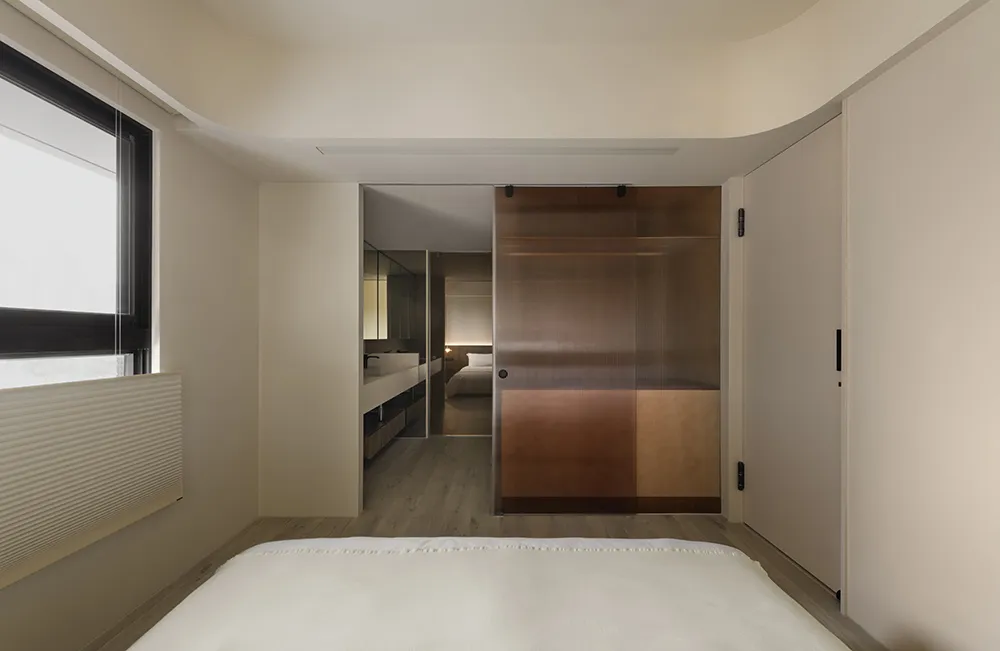 Modern minimalist bedroom featuring a wooden floor and furniture.