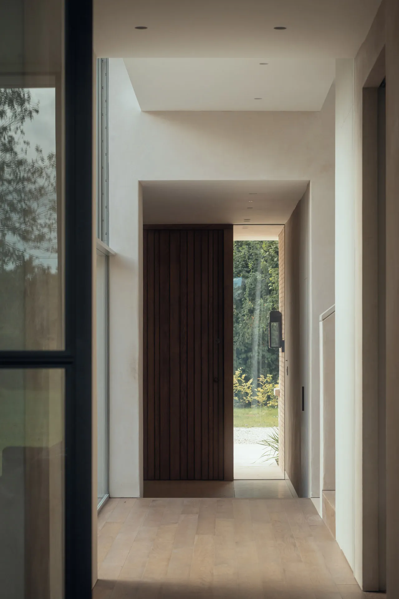 A modern entrance featuring a wooden door with a view of the garden.