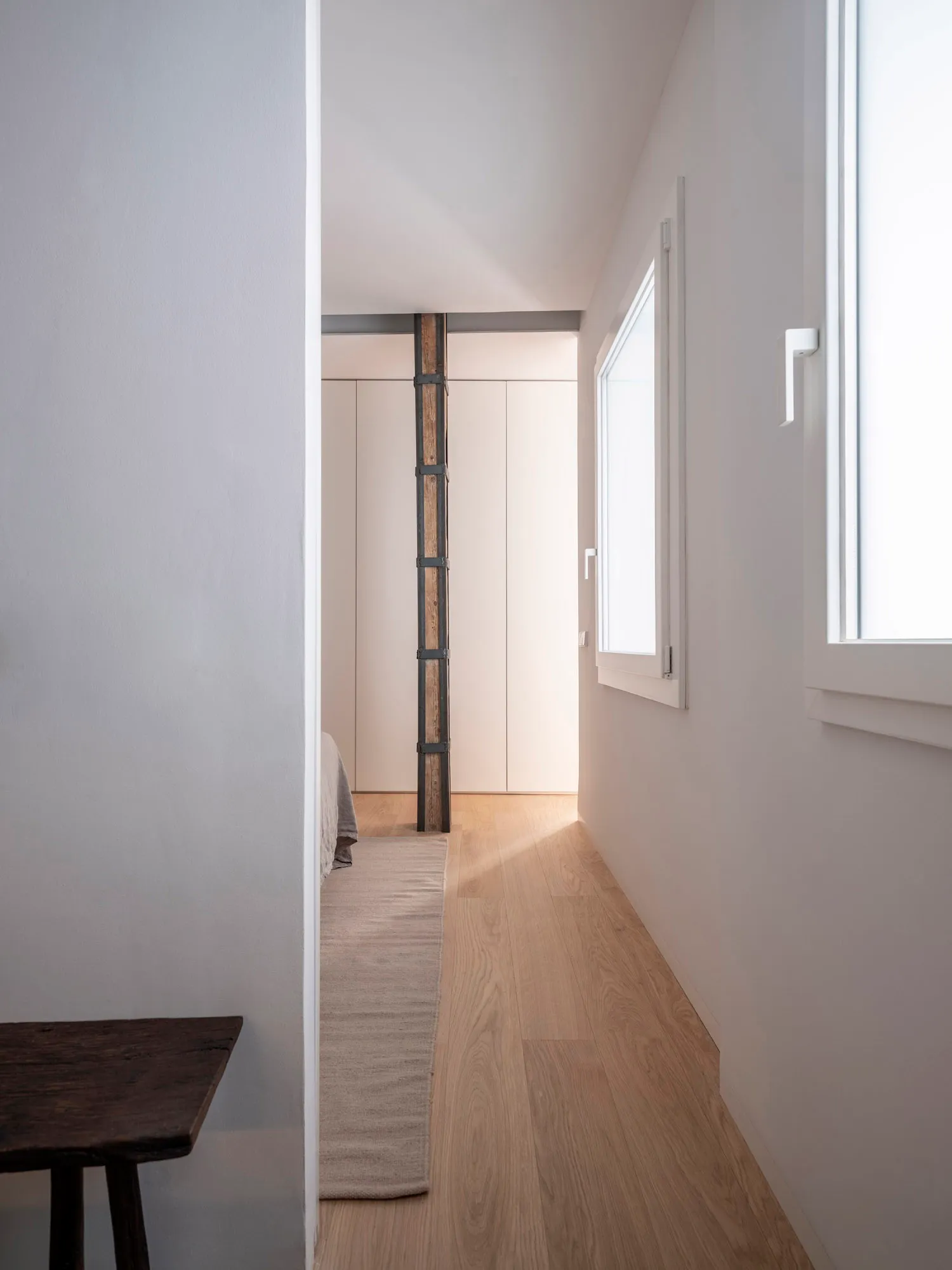 Minimalist bedroom featuring wood flooring and wooden furniture.