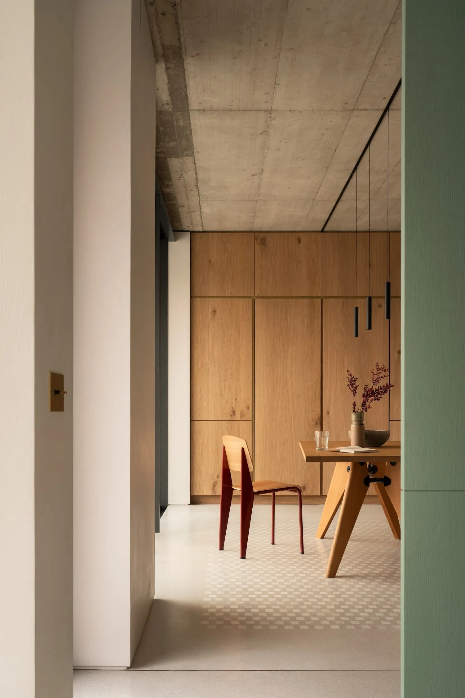 A minimalistic dining area with wooden elements and a concrete ceiling.