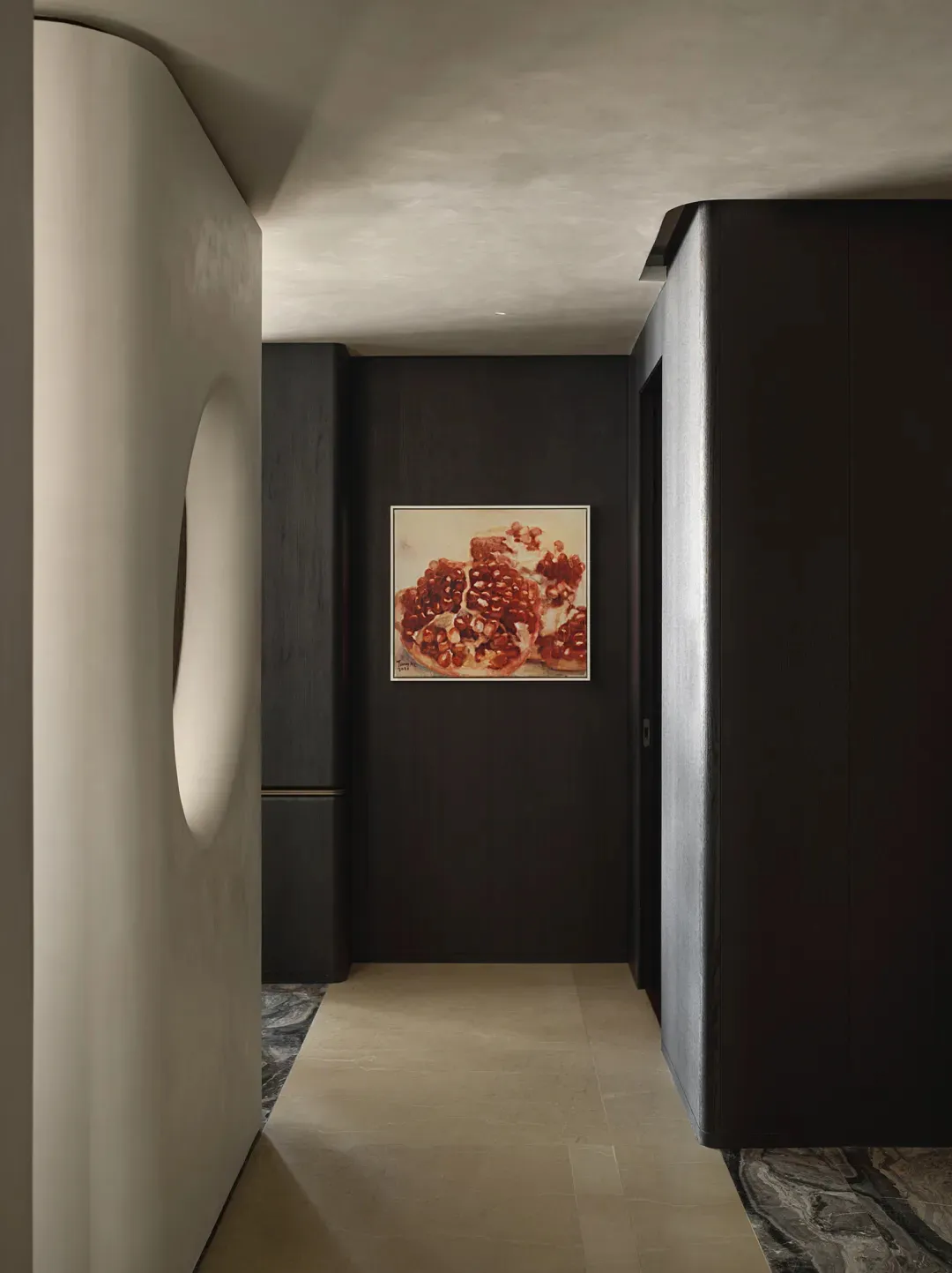 A minimalist corridor with dark wooden walls and stone flooring, featuring a framed painting of a pomegranate interior.