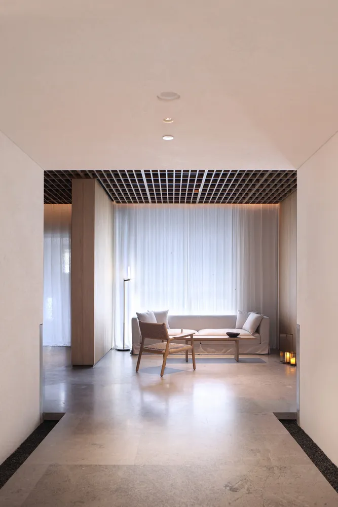 Modern minimalist living room with sandstone floor, white curtains, and white furniture.