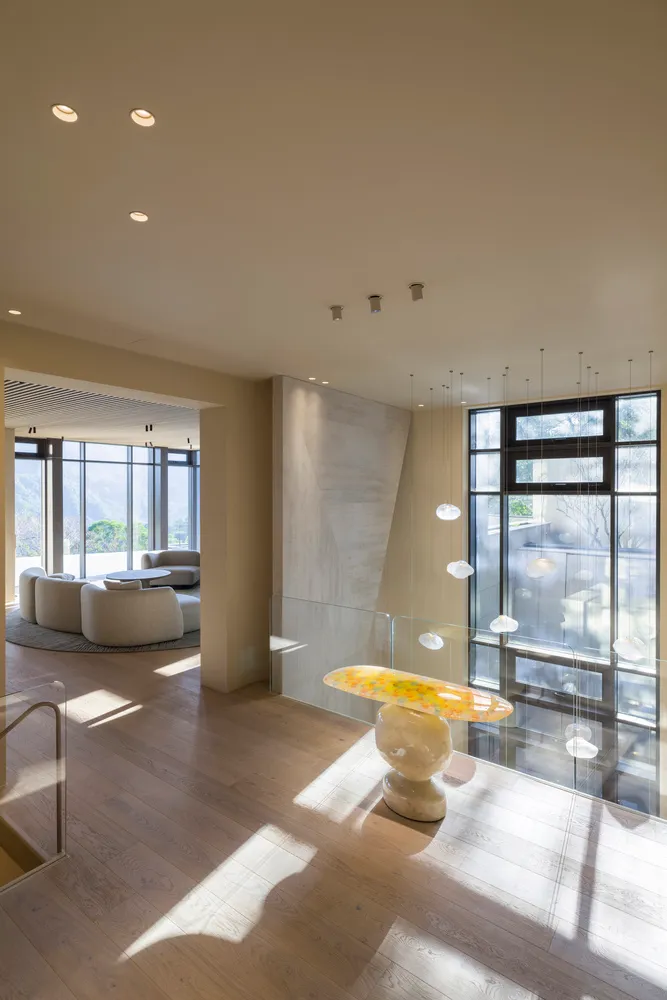Modern minimalist living room with wooden flooring and large windows.