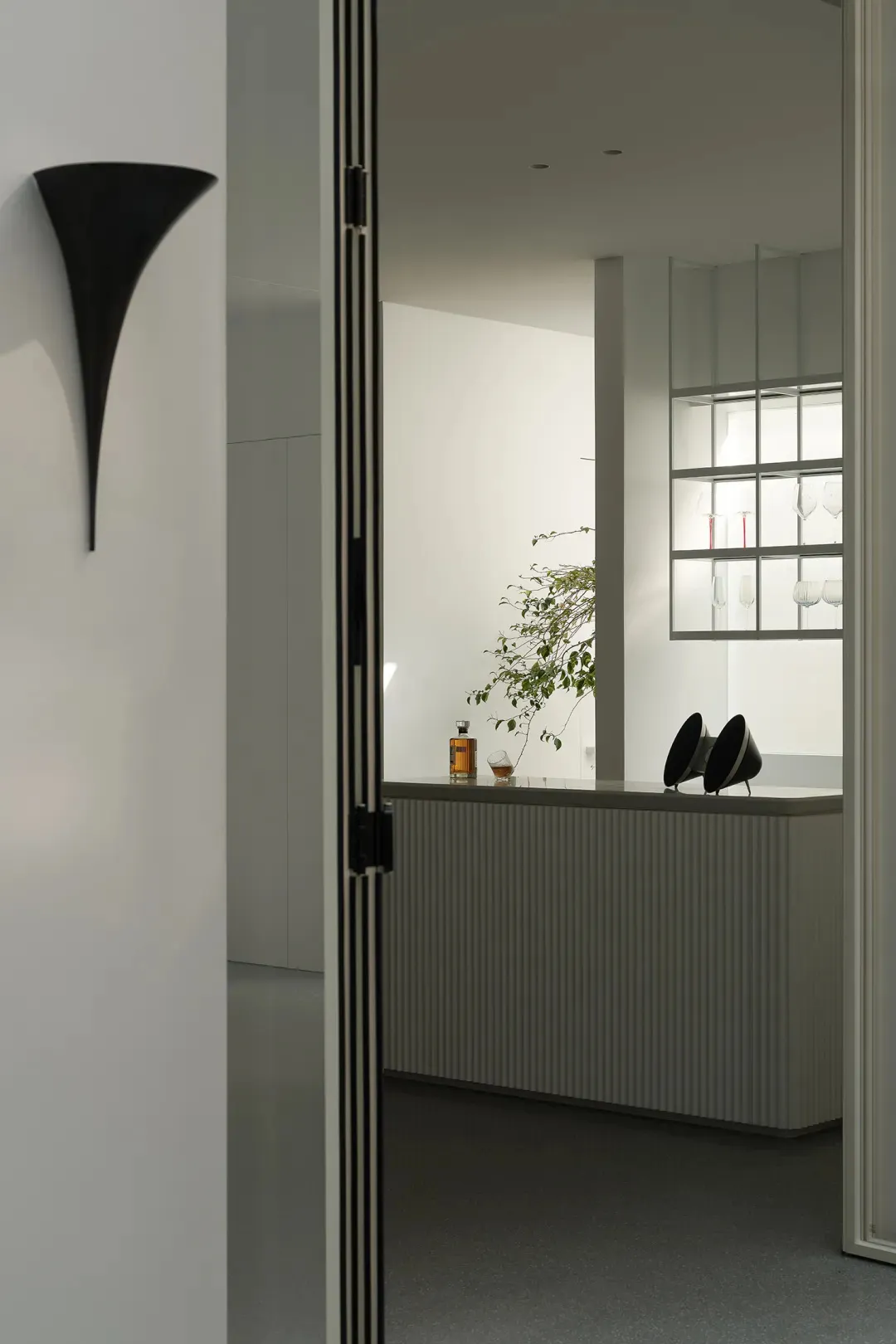 Modern minimalist living space with concrete walls and a sleek, contemporary bar area.